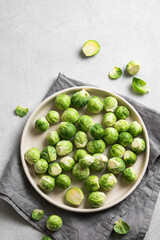 Fresh brussels sprouts in a plate on a light gray background with napkin. Vegetarian healthy food concept.