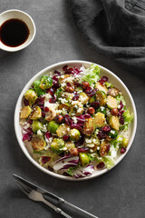 Vegetarian salad of roasted brussels sprouts with lettuce, quinoa, nuts and cranberries in a plate