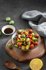 Brussels sprouts with chorizo ​​sausages, nuts and sesame seeds. Concept nutritious asian dish in a bowl on a wooden board