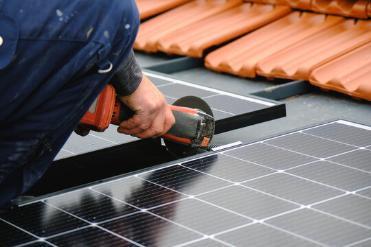 "Worker Installing Solar Panels: Using a Grinder on Roof Mounting Structure"