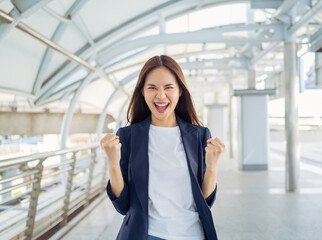 Businesswoman raises arms and fists clenched with shows strong powerful, celebrating victory...