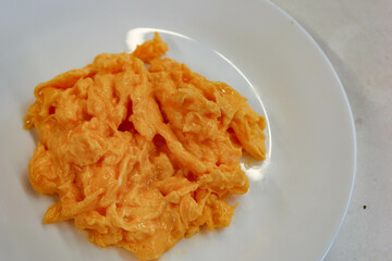 close up of fried scramble egg on a white plate with copy space