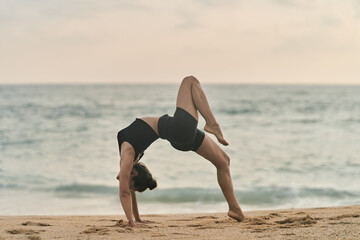 Beautiful girl doing yoga at the beach. High quality photo