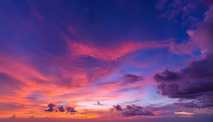 Fototapeta premium 夕暮れ時に広がる紫や赤の空が、ゆっくりと流れる雲と共に静かで美しい風景を描く背景。