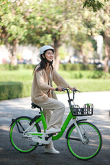A woman is riding a green bicycle with a basket