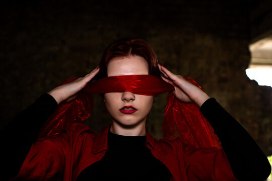 Portrait of a woman. Red lips. Red blindfold. Emotions. Dark background.