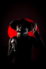 A woman in a mask and Japanese traditional headdress sugegasa poses with a samurai sword. Japanese culture concept. Samurai. Katana.