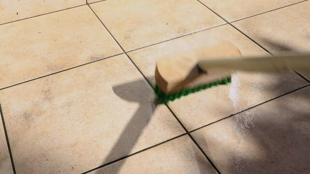 濡れたタイルをデッキブラシでこする