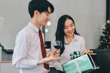 full length view of a group of business team wearing red Santa hat and exchange gift box together in the office for Christmas.