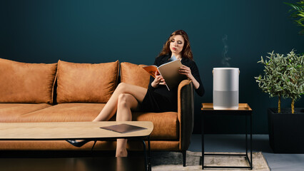 Young well dressed woman sits on couch in lobby and reading magazine