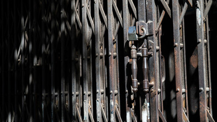 An aged, locked metal gate featuring intricate patterns and shadow play, symbolizing closure and...