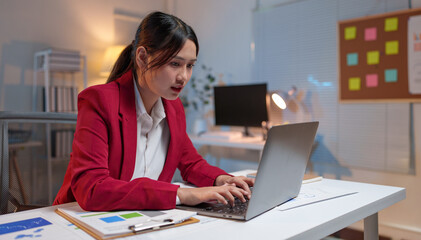Asian business woman, attractive office worker Checking documents financial business information Marketing works with reports, income, company taxes, contacting customers with mobile phones online.