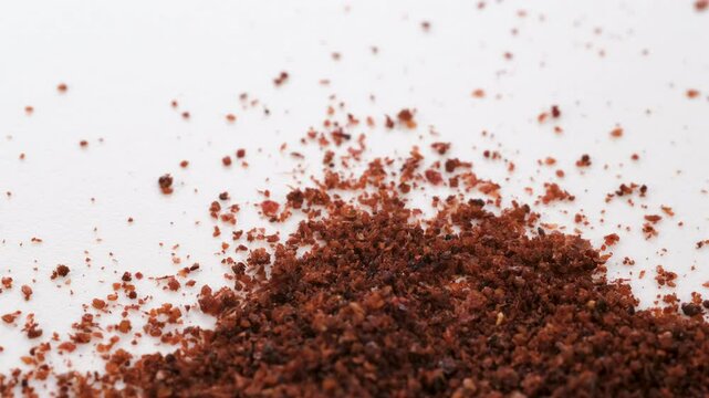 Top view, macro. Heap of scattered dry red sumac powder, Slider shot. Shallow depth of field, selective focus. Ingredients, meat seasoning, cooking, spices, flavor concepts. 4k