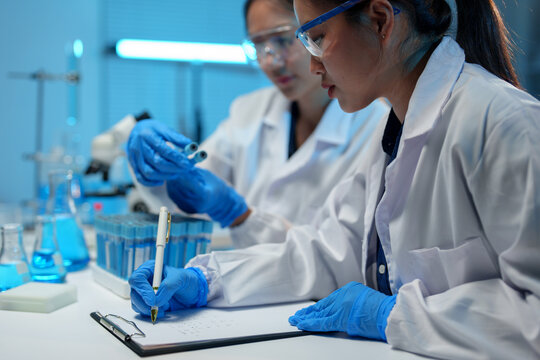 Medical laboratory Biology research development Advanced equipment Two female scientists working using test tubes blue solution Analyze biochemical samples in a medical science laboratory.