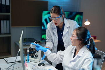 Two Asian female scientists talk Discuss concepts and use PC in evaluating research data in Medical...