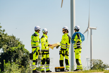 Four young male wind farm engineers work inspecting field systems.Wind turbine engineer inspection and wind turbine inspection progress at construction site.