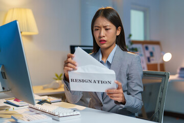 Asian female office worker is stressed, sad, packing up things, documents, personal items. Being...