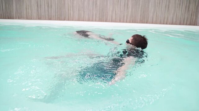Two people practicing swimming techniques in a pool, focusing on coordination and teamwork in aquatic environment.
