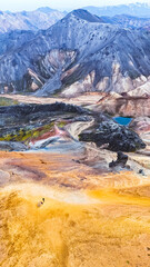Colorful Icelandic mountain landscape. Tourists explore the vibrant, geothermal terrain of Iceland under a clear sky, showcasing stunning natural colors.
