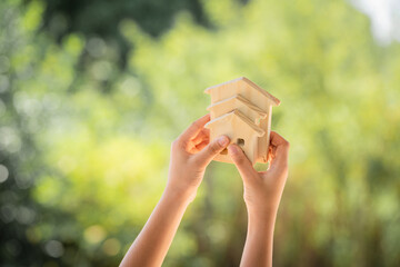 Man hand hold for select the three home model on sunlight in the public park, Loan for real estate or saving money for buy a new house to family in the future concept.