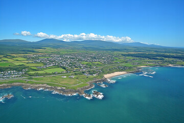 Obraz premium Stunning Irish Coastline with Rolling Green Hills, Dramatic Cliffs, Turquoise Ocean Waves, and Bright Blue Sky Perfect for Travel and Photography