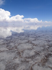 Flooded salar de Uyuni with mirror effect. Reflection of clouds in the water in the salt flat in Bolivia, south America. Idyllic travel destination in february.  landscape with copy space and sunlight