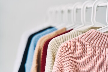 multicolored women's woolen sweaters on hangers. Sale in a fashion store. High quality photo