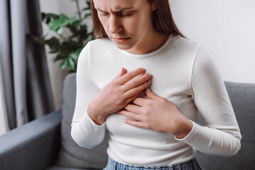 Acid reflux disease. Young woman sit on sofa have symptom gastroesophageal, esophageal, stomach...