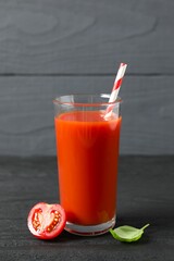 Tomato juice in a glass and fresh tomatoes on the table
