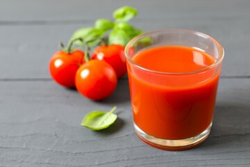 Tomato juice in a glass and fresh tomatoes on the table