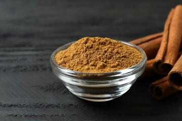 Cinnamon sticks and cinnamon powder in a bowl on a wooden background