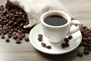 Cup of coffee and coffee beans on wooden background