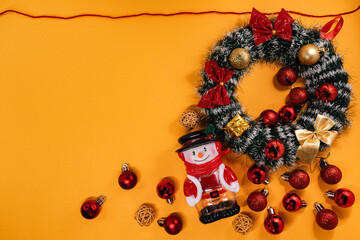 Cheerful Christmas arrangement featuring a wreath, snowman, and baubles framed by a red cord, perfect for holiday themes.