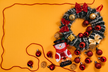 Cheerful Christmas arrangement featuring a wreath, snowman, and baubles framed by a red cord, perfect for holiday themes.