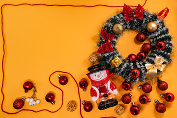 Cheerful Christmas arrangement featuring a wreath, snowman, and baubles framed by a red cord, perfect for holiday themes.