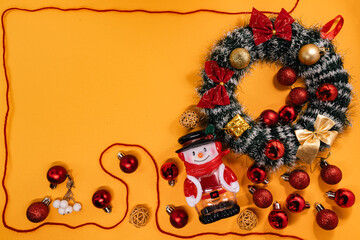 Cheerful Christmas arrangement featuring a wreath, snowman, and baubles framed by a red cord, perfect for holiday themes.