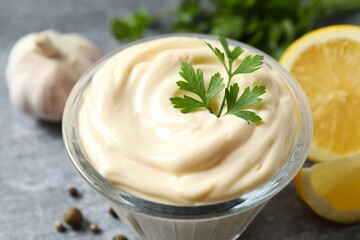 Bowl with mayonnaise and ingredients for cooking on gray background