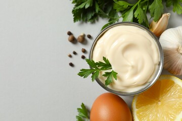 Bowl with mayonnaise and ingredients for cooking on gray background