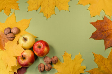 Apples and autumn leaves creatively arranged in a border style on a green surface, perfect for seasonal themes.