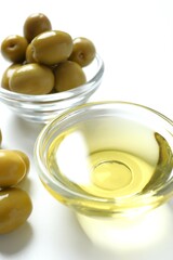 Bowl of fresh olive oil and olives on white background 
