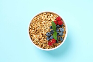Delicious granola with berries on a color background