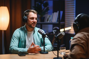 Podcasters enjoying happy conversations with online listeners in studio, covering wide range of...