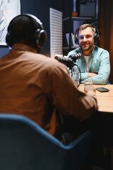 Man recording podcast using high tech microphones to interview guest, ensuring flawless video and...