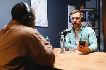 Podcasters enjoying happy conversations with online listeners in studio, covering wide range of...