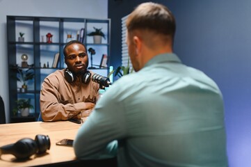Man recording podcast using high tech microphones to interview guest, ensuring flawless video and...