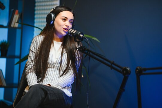 Female podcaster in headphones interviewing man guest using microphone, smiling, recording and broadcasting audio podcast in studio. Content creator, blogging