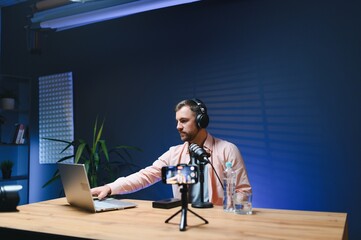 vlogger using smartphone to film podcast in studio. blogger with mobile phone, microphone and...