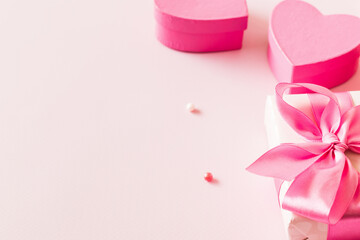 Pink hearts and gift box with ribbon on a light pink background