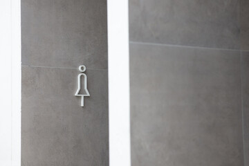 The women's restroom sign is installed on the wall at the entrance to the restroom. A female symbol is attached to the wall. 
