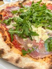 closeup pizza with prosciutto or parma ham, arugula or rocket salad